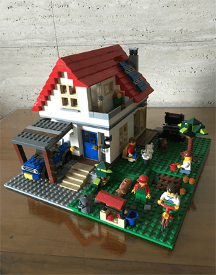 A lego house with a barbeque pit and a small farm and a solar panel on the roof